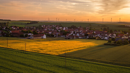 Golden hour over a small viallge with wind turbines in the background