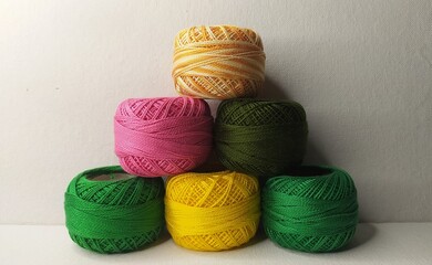 Bunch of double shaded Multicolor mercerized knitting cotton crochet yarn small thread ball or spool stacked together on white table background with copy space. Stitch, needlework, embroidery concept.