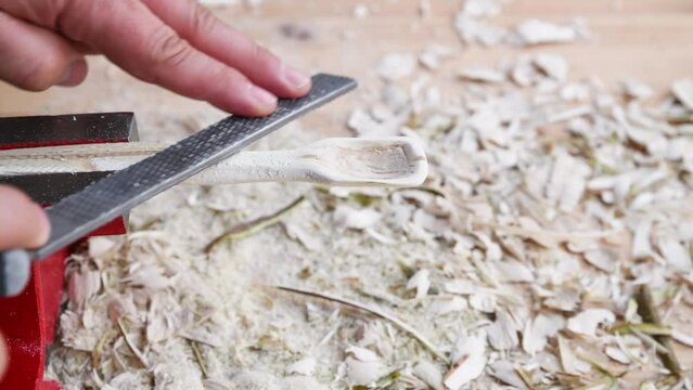 Footage of a wooden spoon carving with wood rasp on a workbench with wood chips, Germany