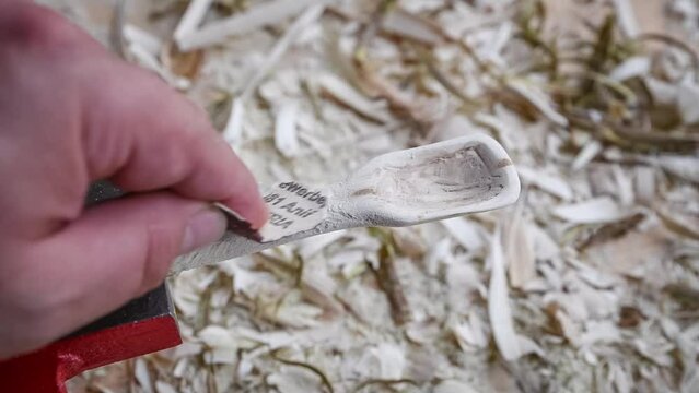 Filmmaterial von einem Holzl&ouml;ffel schnitzen mit Schleifpapier auf einer Werkbank mit Holzsp&auml;ne, Deutschland