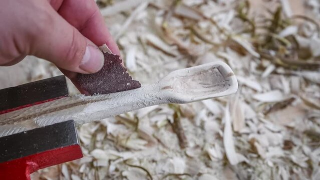 Filmmaterial von einem Holzl&ouml;ffel schnitzen mit Schleifpapier auf einer Werkbank mit Holzsp&auml;ne, Deutschland