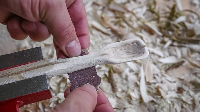 Filmmaterial von einem Holzl&ouml;ffel schnitzen mit Schleifpapier auf einer Werkbank mit Holzsp&auml;ne, Deutschland
