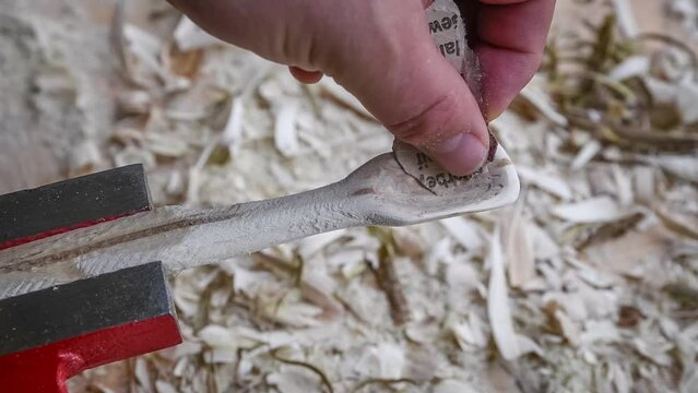 Filmmaterial von einem Holzl&ouml;ffel schnitzen mit Schleifpapier auf einer Werkbank mit Holzsp&auml;ne, Deutschland
