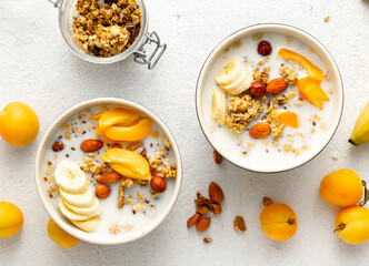 Healthy breakfast cereal top view. Granola breakfast with fruits, nuts, milk and peanut butter in...