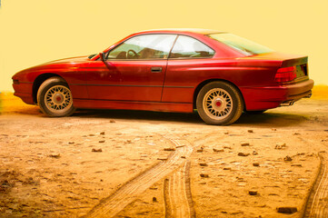 car on the beach
red retro car in profile on the sand on a yellow background
