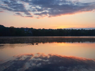 Landscape of Lake Baldeneysee at sunrise. Colorful reflections on the water and a family of ducks...