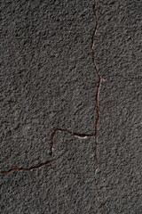 Gray wall with a crack. Texture of rough plaster with uneven granular coating