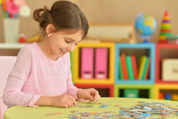 Portrait of cute girl collecting puzzle pieces