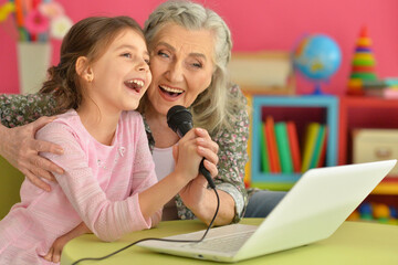 Portrait of grandmother and daughter singing karaoke