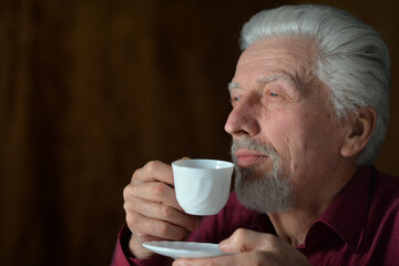 Close-up portrait of senior man drinking at home