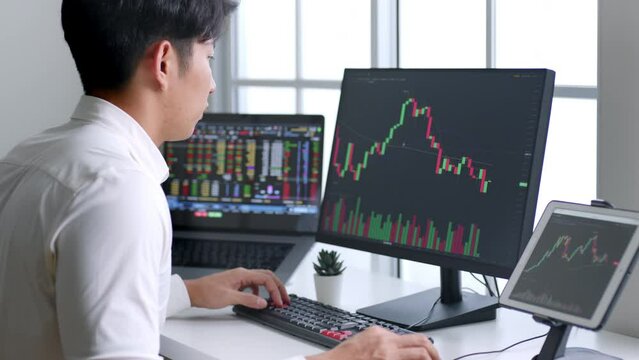 Young Asian investor watching the change of stock market on computer laptop screen.