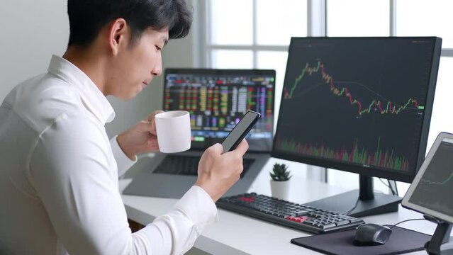 Young Asian investor watching the change of cryptocurrency and stock market on smartphone.