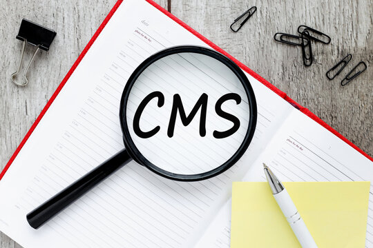 CMS (Content Management System) text on magnifier glass on open notepad