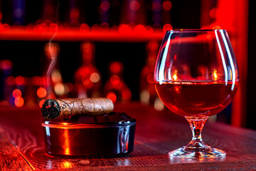 Cigar, elegant glass of brandy on the bar counter. Alcoholic drinks, cognac, whiskey, port, brandy,...