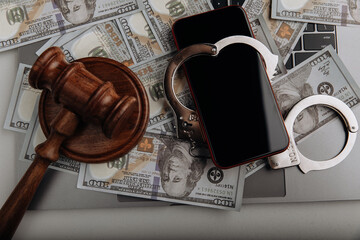 Smartphone with handcuff on a dollar banknotes and judge gavel. Cyber crime and law concept