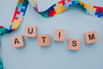 Colorful ribbon and blocks with AUTISM word on blue background. World autism awareness day concept