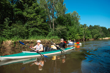 Family kayak trip. Man and woman and elderly couple senior and seniora rowing boat on the river, a water hike, a summer adventure. Eco-friendly and extreme tourism, active and healthy lifestyle