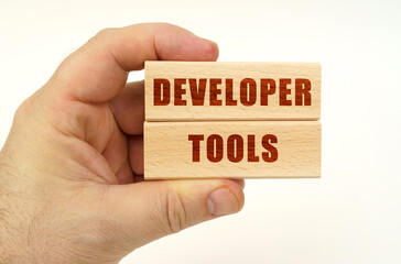 On a white background, a hand that holds wooden blocks with the inscription - Developer Tools