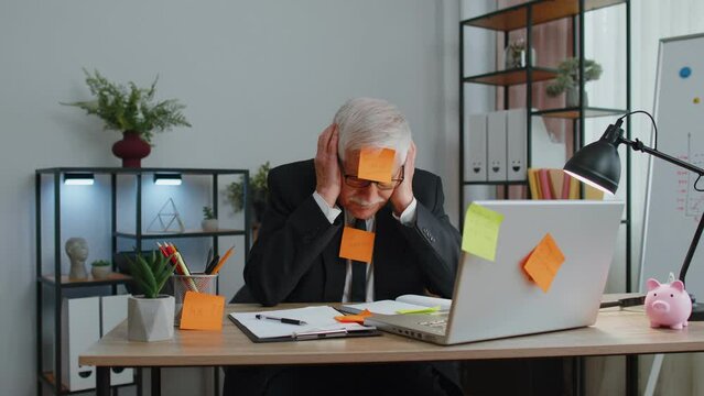 Tired exhausted fatigue senior business man office employee manager sits in office table with laptop sticky notes sticks with many tasks inscription help, feels sad boredom overworked multitasking