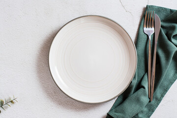 Empty ceramic plate, cutlery and cloth on a gray background. Eco concept. Top view.