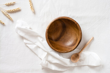 Empty wooden bowl, spoon and ear on cloth. Top view. Eco-friendly concept