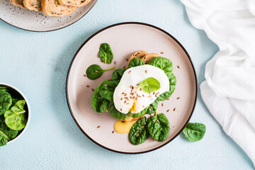 Appetizing sandwich with poached egg, spinach and flax seeds on a plate. Flexetarian Diet. Top view