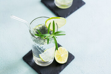 Refreshing drink water with lime and rosemary in glasses with eco straw. Close-up. Copy space