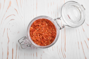 dried carrots in a jar on a white wooden background