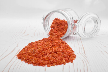 dried carrots scattered from a jar on a white wooden background