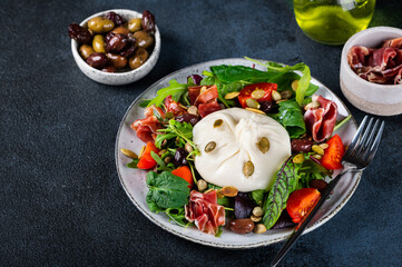 Burrata, Italian fresh cheese made from cream and milk of buffalo or cow. Burrata salad with tomatoes and salad mix. Healthy eating concept. Keto diet salad.