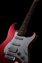 Red electric guitar on a black background. Fender