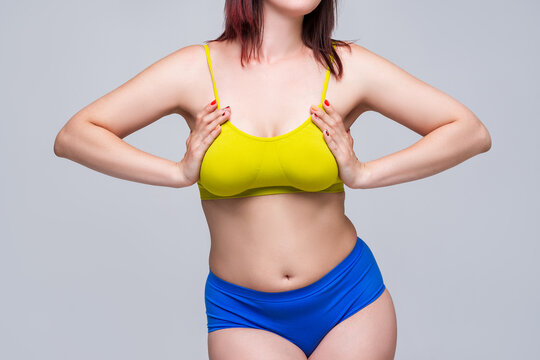 Woman in yellow top bra with big natural breasts on gray background