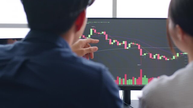 Young Asian investors analyzing about stock market and cryptocurrency investment from graph in computer laptop together.