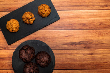 Cookies of different taste on dark slate plate, light wood background. Top view, flat lay, space for text.