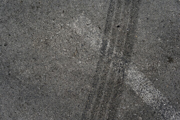 Asphalt texture with white line and tire marks. Smooth asphalt road. Tarmac dark grey grainy road...