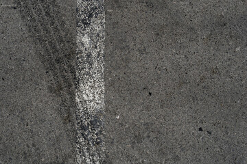 Asphalt texture with white line and tire marks. Smooth asphalt road. Tarmac dark grey grainy road background.Top view - 502098460