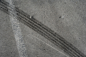 Asphalt texture with white line and tire marks. Smooth asphalt road. Tarmac dark grey grainy road background.Top view - 502098478