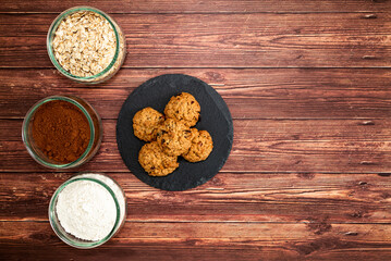 Preparation of homemade cookies with ingredients on dark wooden background. Homemade food concept with top view, space for text.