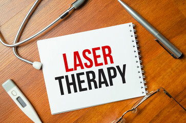 Laser therapy word on the white notepad on the wooden desk