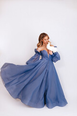 Happy young woman in a blue puffy dress holds a white dove symbol of peace on a white background....