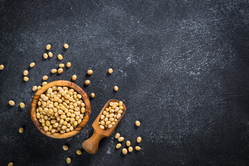 Soy is a source of plant based protein. Vegan food. Soya beans in the wooden bowl at black stone table.