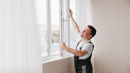 a repairman repairs, adjusts or installs metal-plastic windows in the apartment.