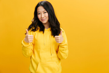 Good idea. Happy cute Asian student young woman in yellow hoodie sweatshirt show thumbs up Like...