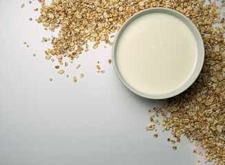 Scattered oat flakes on white background with milk in the bowl.
Oat flakes isolated on white background. Healthy food concept. Energy breakfast.
