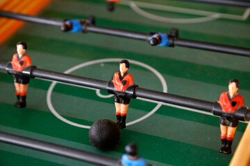 Foosball. Soccer hall game. Traditional game. Soccer game. Table with soccer players. Old wooden foosball. Football players. Dolls with blue and red painted T-shirts. Metegol