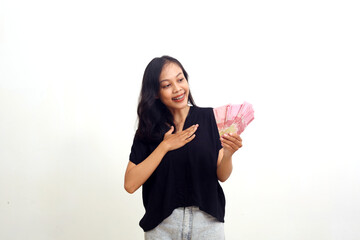 Asian young woman feels relieved and happy while holding Indonesian money. Isolated on white - obrazy, fototapety, plakaty