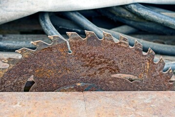 part of an old round rusty iron brown circular saw on a metal table in a workshop