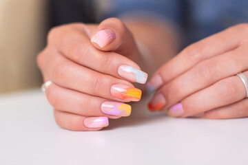 Fototapeta premium Beautiful female hands with multicoloured manicure nails, pink, blue and orange gel polish