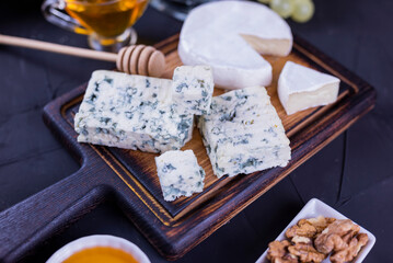 appetizer cheese dor blue and camembert on a wooden board with honey and grapes