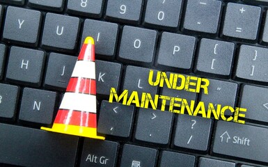 construction cones and laptop keyboards with words under maintenance
